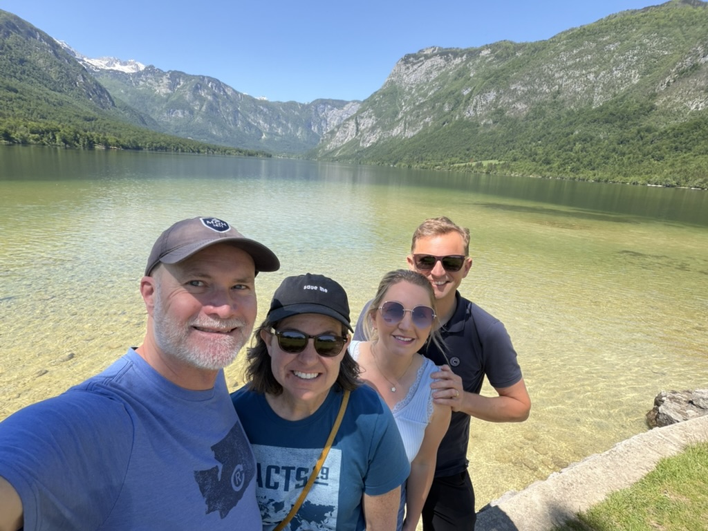 Four people beside a lake and mountains in Slovenia